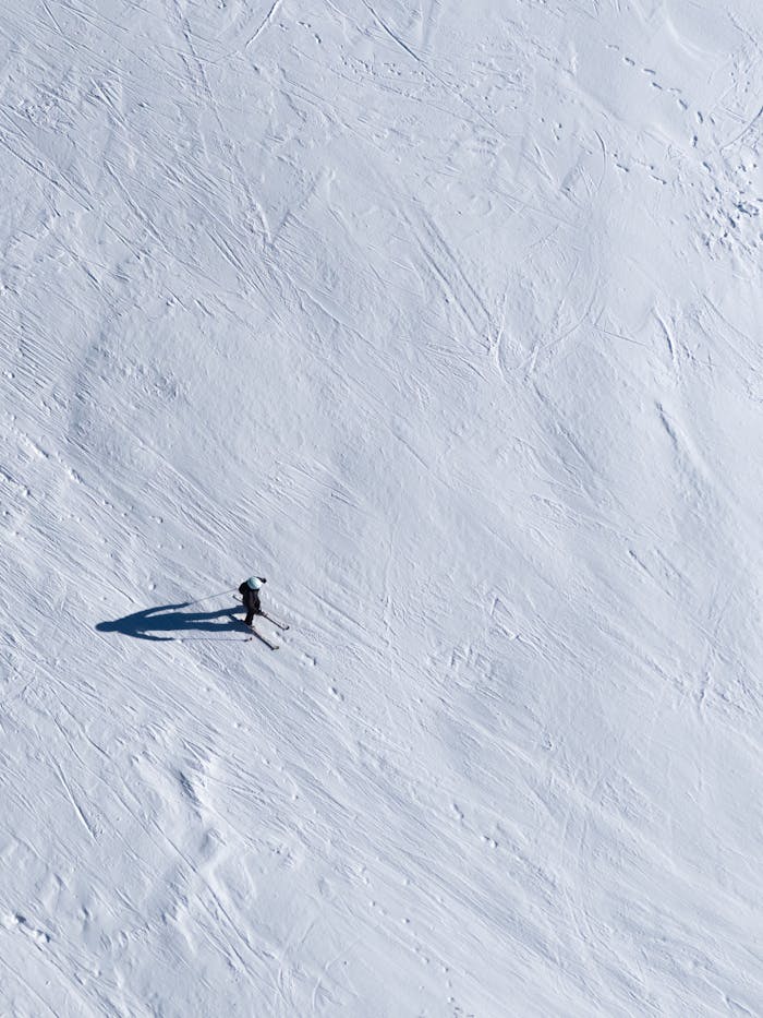 A lone skier navigates a steep snowy hill in this high-angle shot, epitomizing winter adventure.